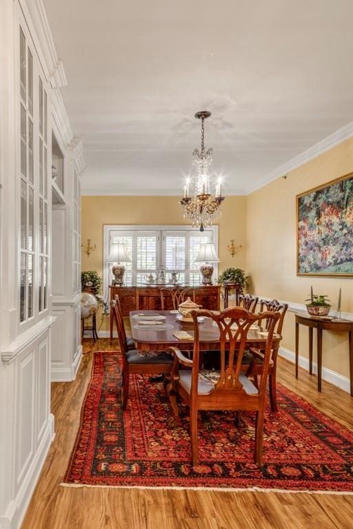 dining space with crown molding, light hardwood / wood-style flooring, and a chandelier