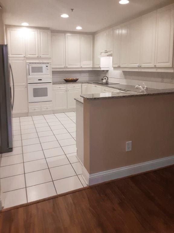 kitchen with kitchen peninsula, white cabinets, and white appliances