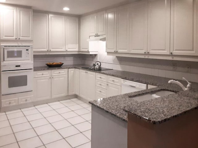 kitchen with white appliances, white cabinetry, dark stone countertops, and sink