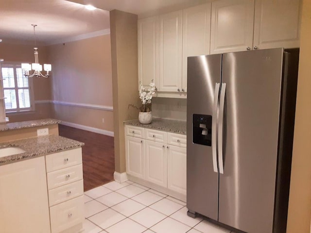 kitchen with white cabinets, stainless steel fridge, light stone countertops, and light tile patterned flooring