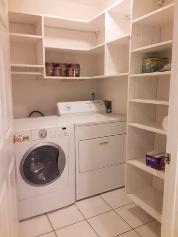 clothes washing area featuring washer and clothes dryer and light tile patterned floors