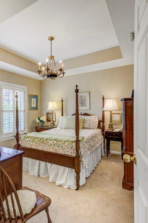 carpeted bedroom with a raised ceiling and a chandelier