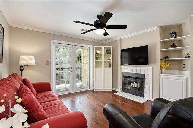 living room with french doors, a tile fireplace, wood finished floors, and crown molding