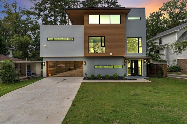 contemporary home with concrete driveway, an attached garage, a lawn, and stucco siding