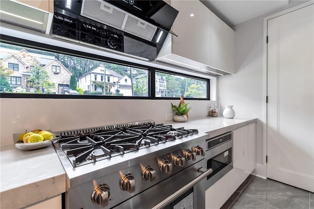 kitchen with marble finish floor, white cabinetry, and high end stainless steel range