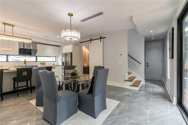 dining space featuring visible vents, baseboards, stairs, and a barn door