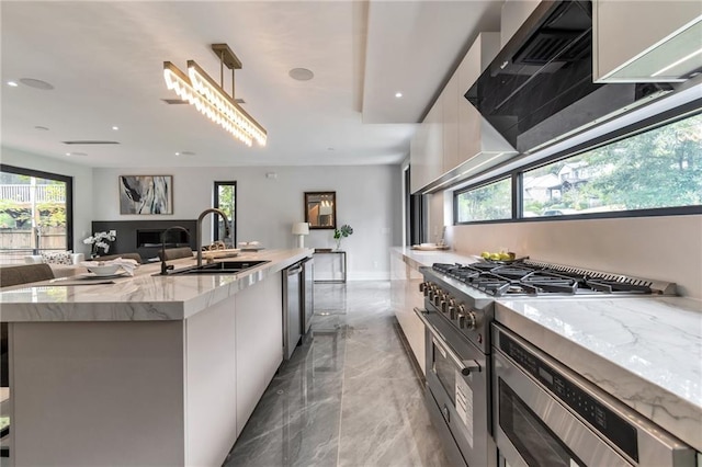 kitchen with range hood, a sink, high end stainless steel range oven, modern cabinets, and open floor plan