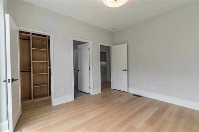 unfurnished bedroom with a spacious closet, visible vents, and light wood-type flooring