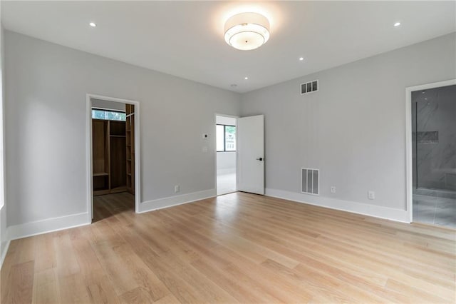 spare room featuring light wood finished floors, visible vents, recessed lighting, and baseboards