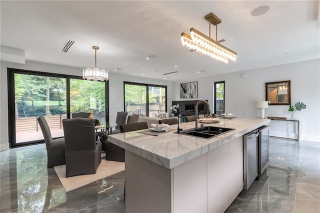 kitchen featuring hanging light fixtures, marble finish floor, modern cabinets, and a sink