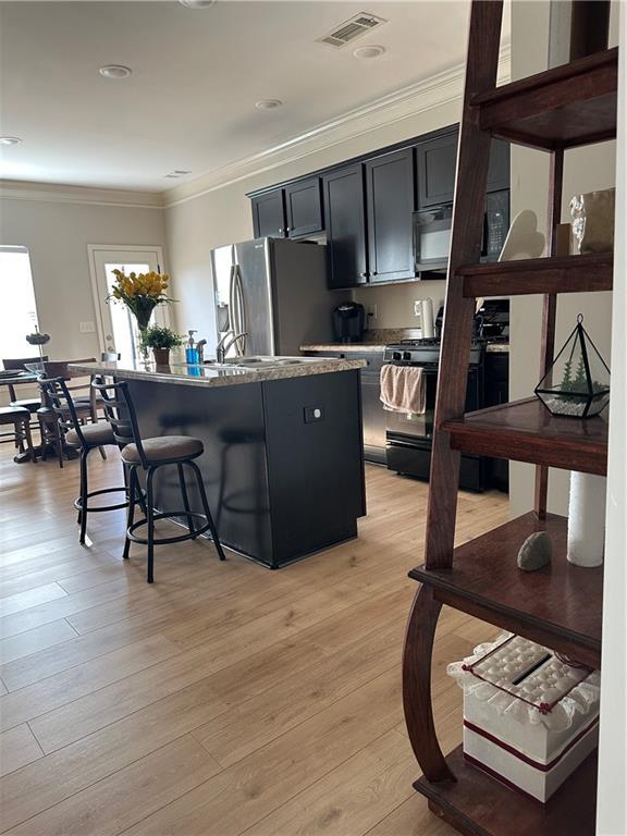 302 Turtle Creek Dr, Winder, GA 30680 - kitchen featuring black appliances, crown molding, a kitchen island with sink, a kitchen breakfast bar, and dark cabinetry