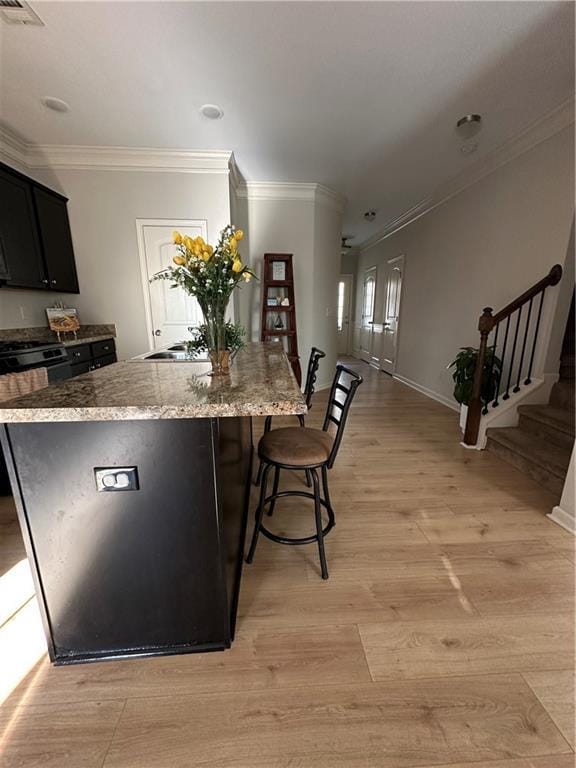 302 Turtle Creek Dr, Winder, GA 30680 - kitchen featuring a kitchen breakfast bar, a kitchen island with sink, crown molding, light stone countertops, and light wood-style flooring
