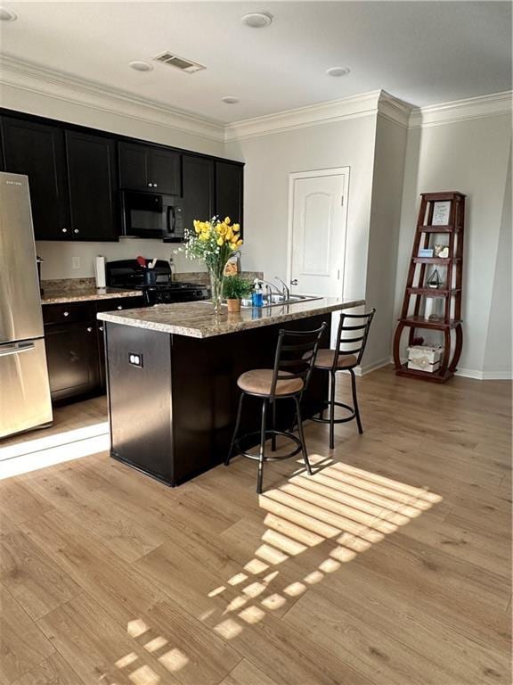 302 Turtle Creek Dr, Winder, GA 30680 - kitchen featuring freestanding refrigerator, range, dark cabinets, black microwave, and an island with sink