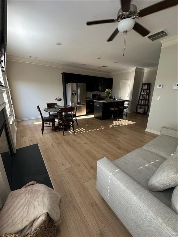 302 Turtle Creek Dr, Winder, GA 30680 - living area with crown molding, ceiling fan, light wood-style flooring, baseboards, and a glass covered fireplace