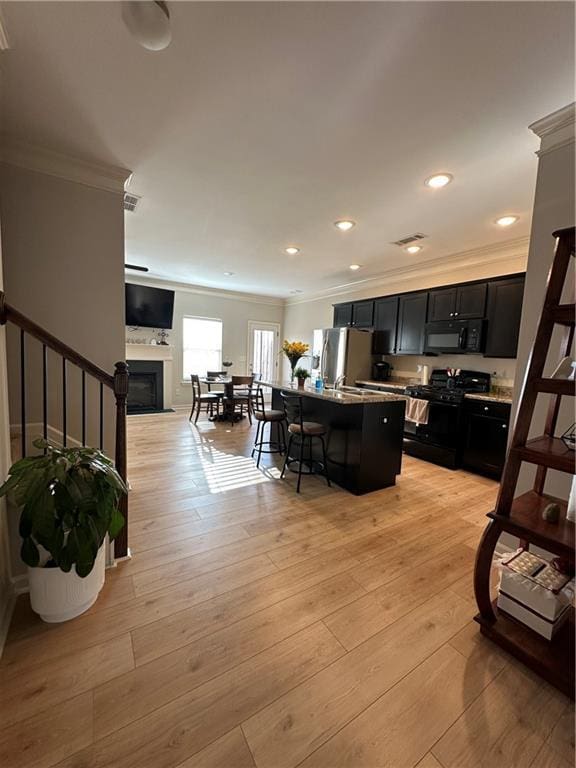 302 Turtle Creek Dr, Winder, GA 30680 - kitchen with black appliances, ornamental molding, dark cabinets, open floor plan, and a breakfast bar area