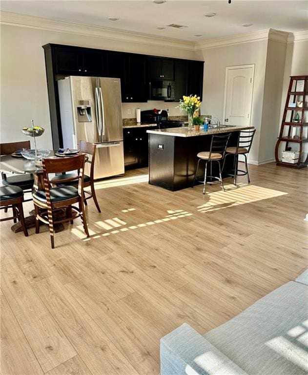 302 Turtle Creek Dr, Winder, GA 30680 - kitchen with stainless steel fridge with ice dispenser, dark cabinetry, crown molding, black microwave, and a kitchen island with sink