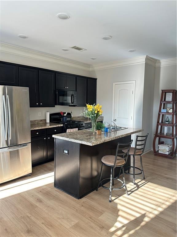 302 Turtle Creek Dr, Winder, GA 30680 - kitchen featuring black appliances, dark cabinetry, a kitchen breakfast bar, light wood-style floors, and ornamental molding