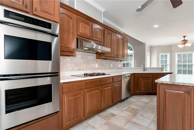 3885 Lake Juliette Dr, Buford, GA 30519 - kitchen with ceiling fan, stainless steel appliances, ornamental molding, under cabinet range hood, and decorative backsplash