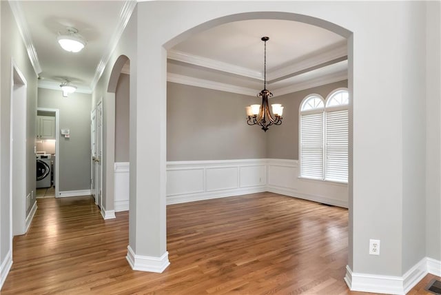 3885 Lake Juliette Dr, Buford, GA 30519 - unfurnished dining area featuring wood finished floors, washer / clothes dryer, ornamental molding, arched walkways, and a chandelier