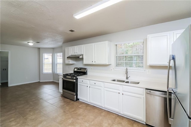 kitchen with appliances with stainless steel finishes, a textured ceiling, white cabinetry, and sink