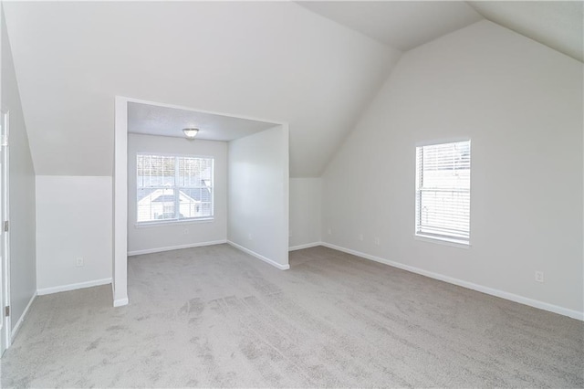 bonus room with a healthy amount of sunlight, lofted ceiling, and light carpet