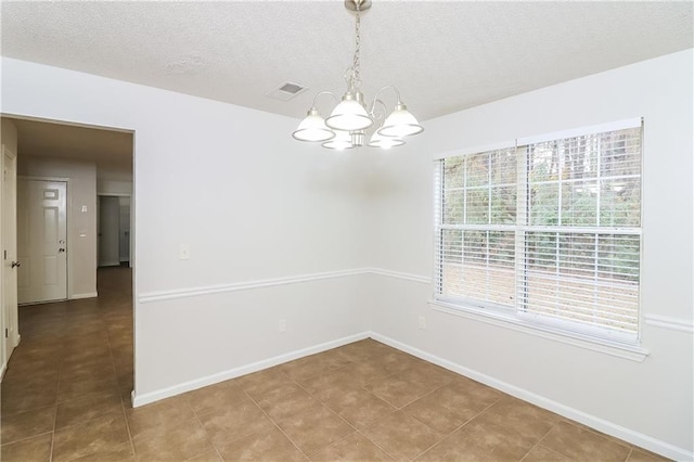 unfurnished room with a chandelier, a textured ceiling, and tile patterned floors