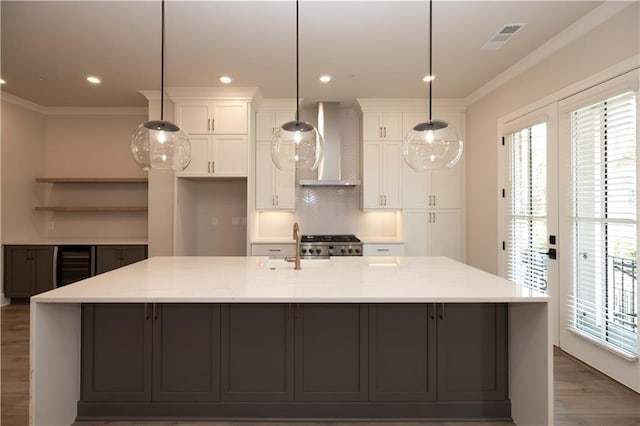 kitchen featuring a spacious island, white cabinets, and wall chimney exhaust hood