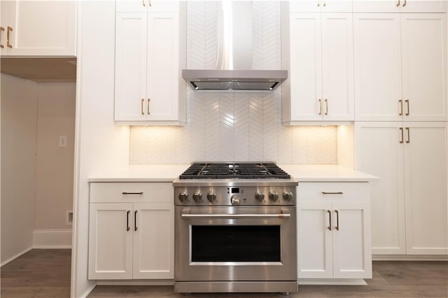 kitchen with wall chimney range hood, hardwood / wood-style floors, tasteful backsplash, white cabinets, and stainless steel range with gas cooktop