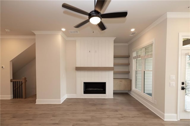 unfurnished living room with a fireplace, crown molding, wood-type flooring, and a healthy amount of sunlight