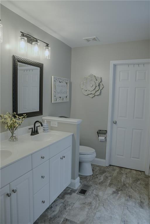 6985 Shane Ln, Cumming, GA 30028 - bathroom featuring double vanity, toilet, and baseboards