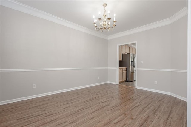 unfurnished room with a chandelier, ornamental molding, wood finished floors, and baseboards