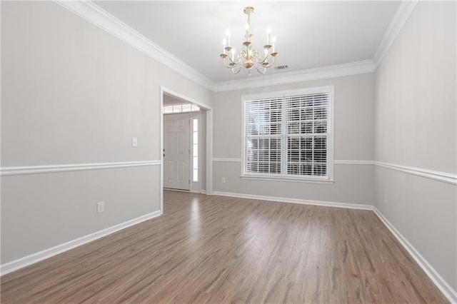 empty room with a chandelier, baseboards, wood finished floors, and crown molding