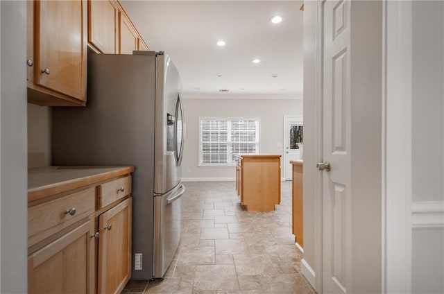 kitchen with crown molding, recessed lighting, freestanding refrigerator, a kitchen island, and baseboards