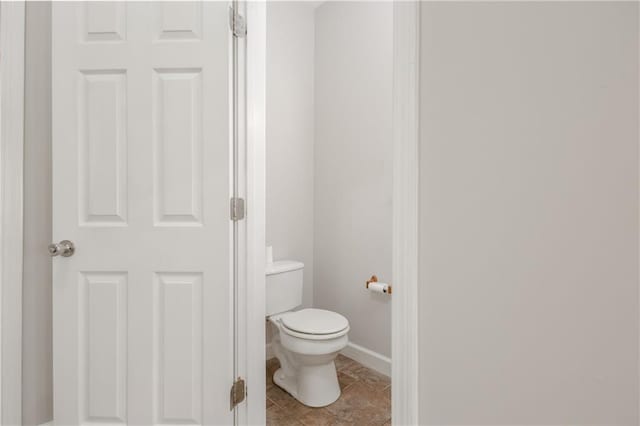 bathroom with tile patterned flooring, baseboards, and toilet