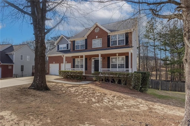 colonial home featuring driveway, an attached garage, covered porch, fence, and brick siding