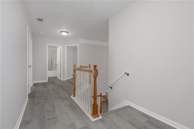 corridor featuring visible vents, wood finished floors, an upstairs landing, and baseboards