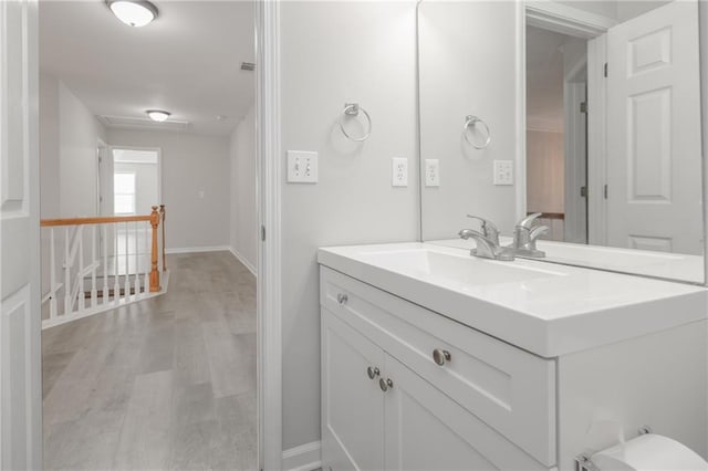 bathroom with visible vents, vanity, baseboards, and wood finished floors