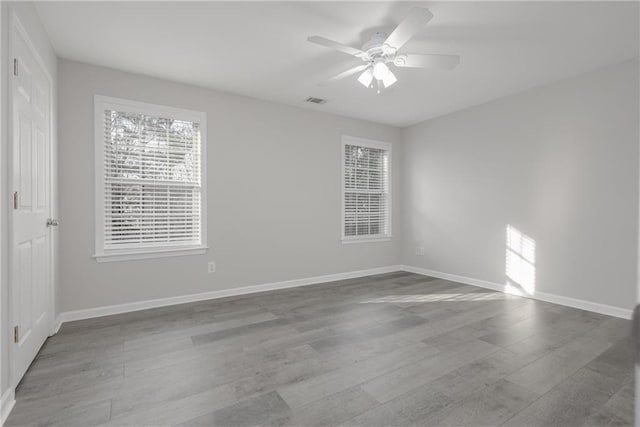 spare room featuring visible vents, wood finished floors, a ceiling fan, and baseboards