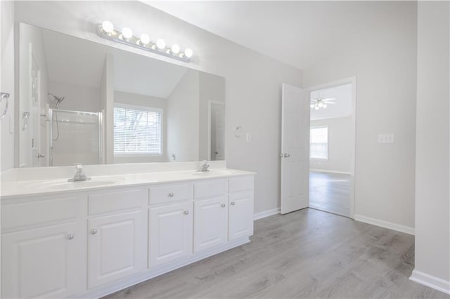 full bathroom with double vanity, a shower, a sink, and wood finished floors