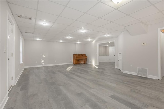 unfurnished living room featuring visible vents, a drop ceiling, and wood finished floors