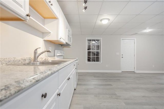 kitchen with white cabinets, a drop ceiling, range, and a sink