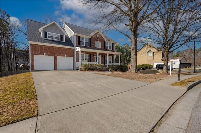 colonial home with an attached garage, covered porch, brick siding, a shingled roof, and concrete driveway