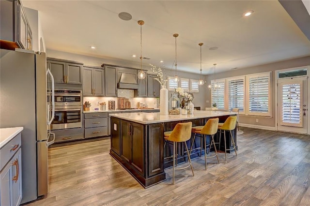13 Clearwater Ct, Hoschton, GA 30548 - kitchen with appliances with stainless steel finishes, premium range hood, light wood finished floors, light countertops, and recessed lighting