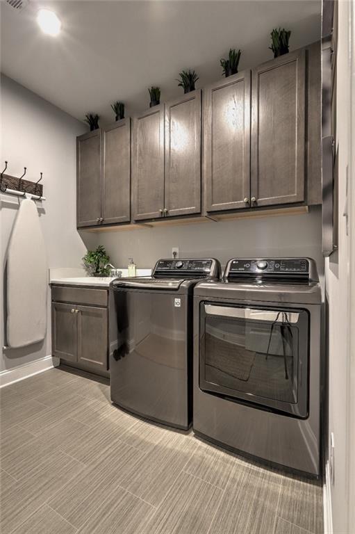 13 Clearwater Ct, Hoschton, GA 30548 - laundry area featuring washing machine and dryer, cabinet space, baseboards, and light colored carpet