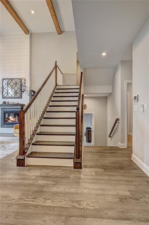 13 Clearwater Ct, Hoschton, GA 30548 - stairs featuring wood finished floors, a glass covered fireplace, beamed ceiling, recessed lighting, and baseboards