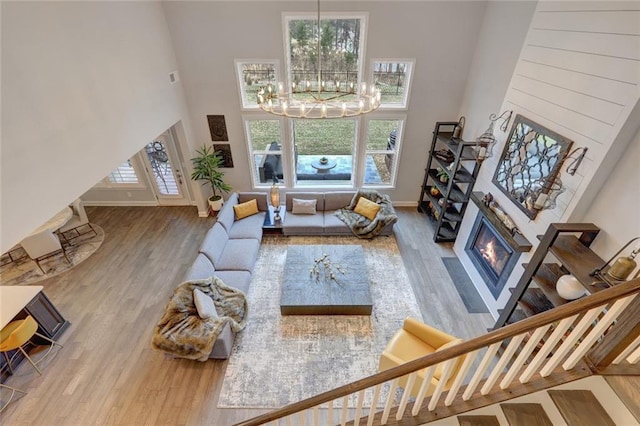 13 Clearwater Ct, Hoschton, GA 30548 - living area featuring a high ceiling, a glass covered fireplace, wood finished floors, a chandelier, and baseboards