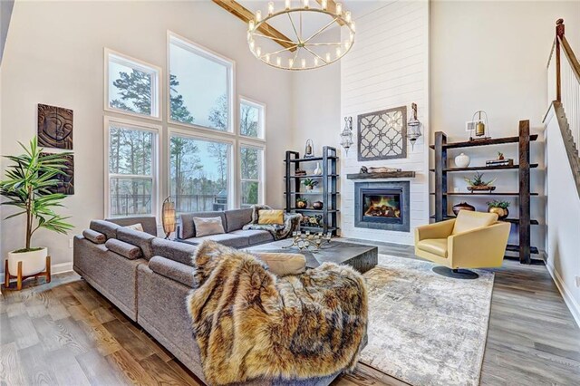 13 Clearwater Ct, Hoschton, GA 30548 - living room with a high ceiling, a chandelier, wood finished floors, a large fireplace, and baseboards