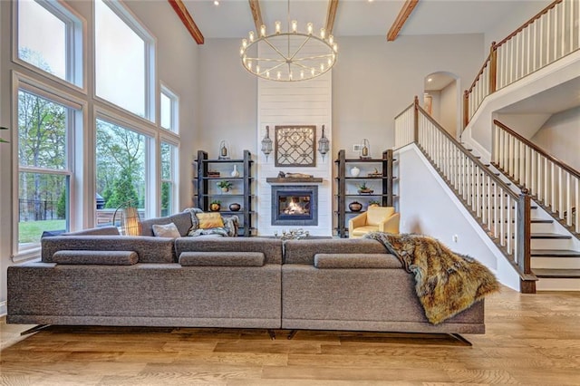13 Clearwater Ct, Hoschton, GA 30548 - living area with a towering ceiling, a chandelier, a glass covered fireplace, stairs, and wood finished floors