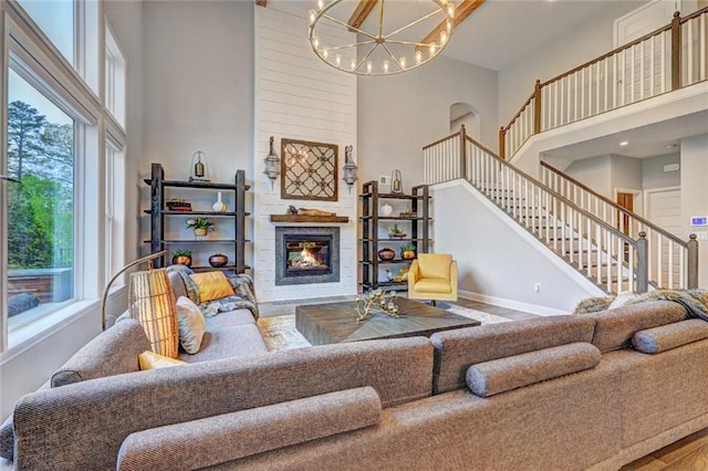 13 Clearwater Ct, Hoschton, GA 30548 - living area with a towering ceiling, a chandelier, baseboards, a glass covered fireplace, and stairway