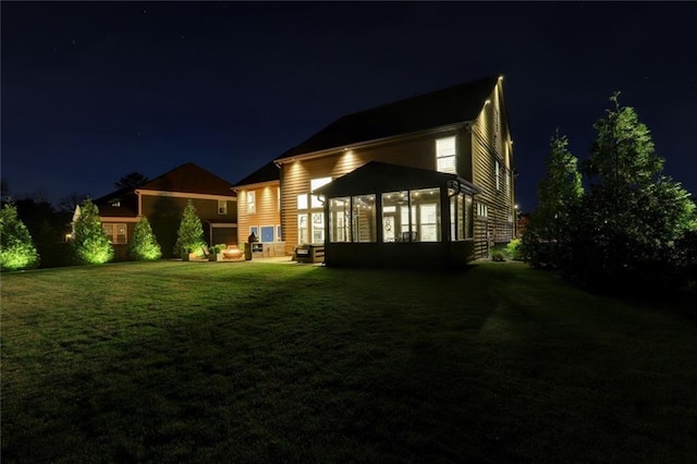 13 Clearwater Ct, Hoschton, GA 30548 - back of house at night featuring a sunroom and a lawn
